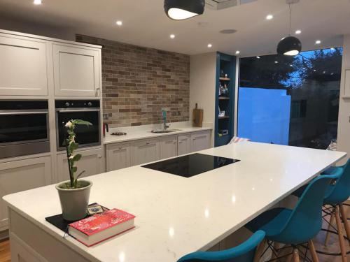 Contemporary new kitchen with brick splashback  teal coloured counter stools